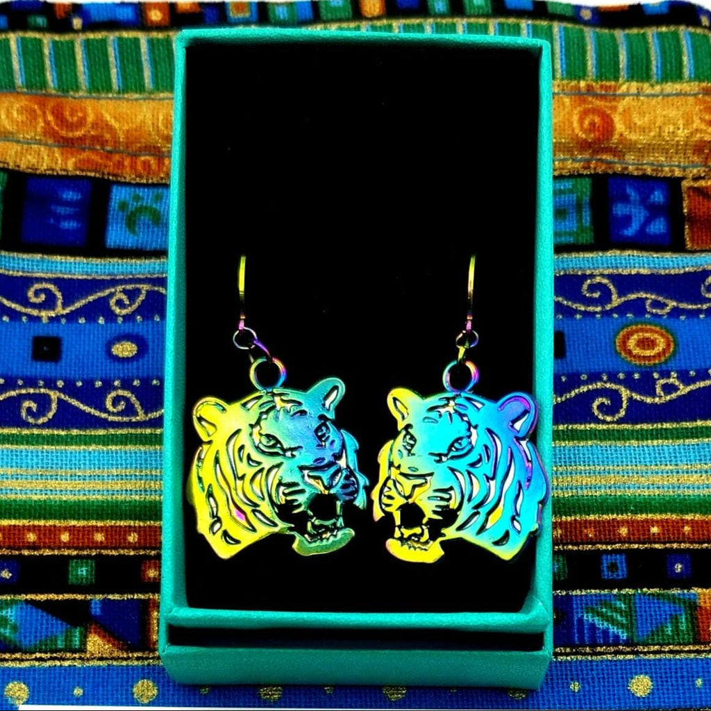 Rainbow Tiger-shaped earrings in a black box on a colorful patterned fabric background
