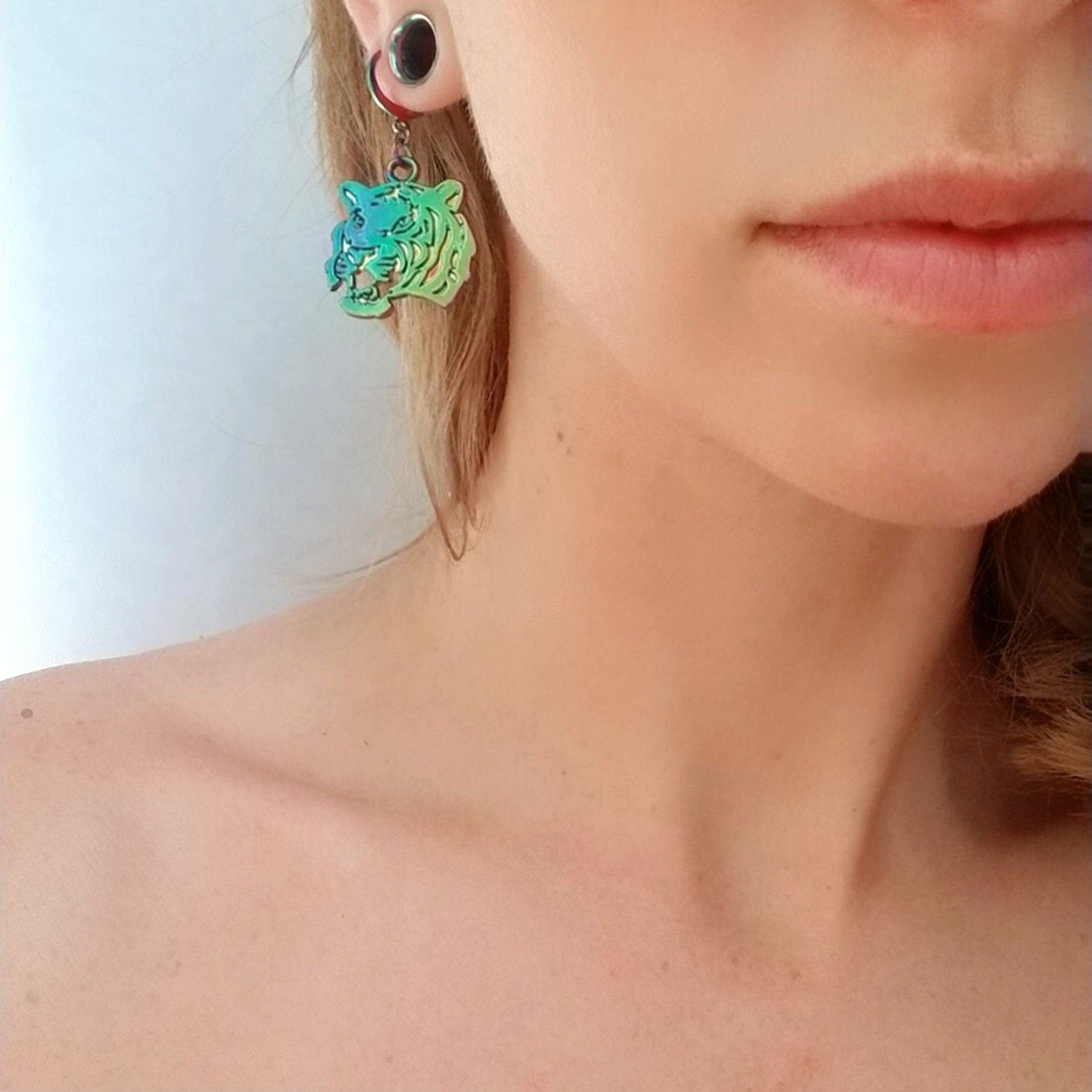 Close-up of a woman wearing a green tiger earring against a neutral background