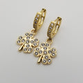 Gold four-leaf clover earrings with clear stones on a light gray background