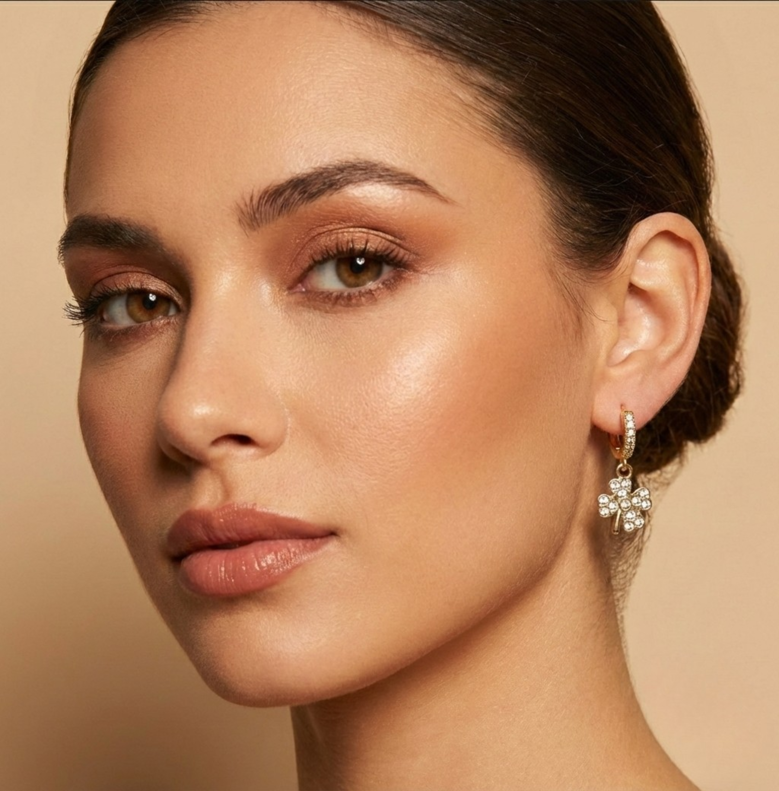 Close-up of a woman wearing a floral earring against a beige background